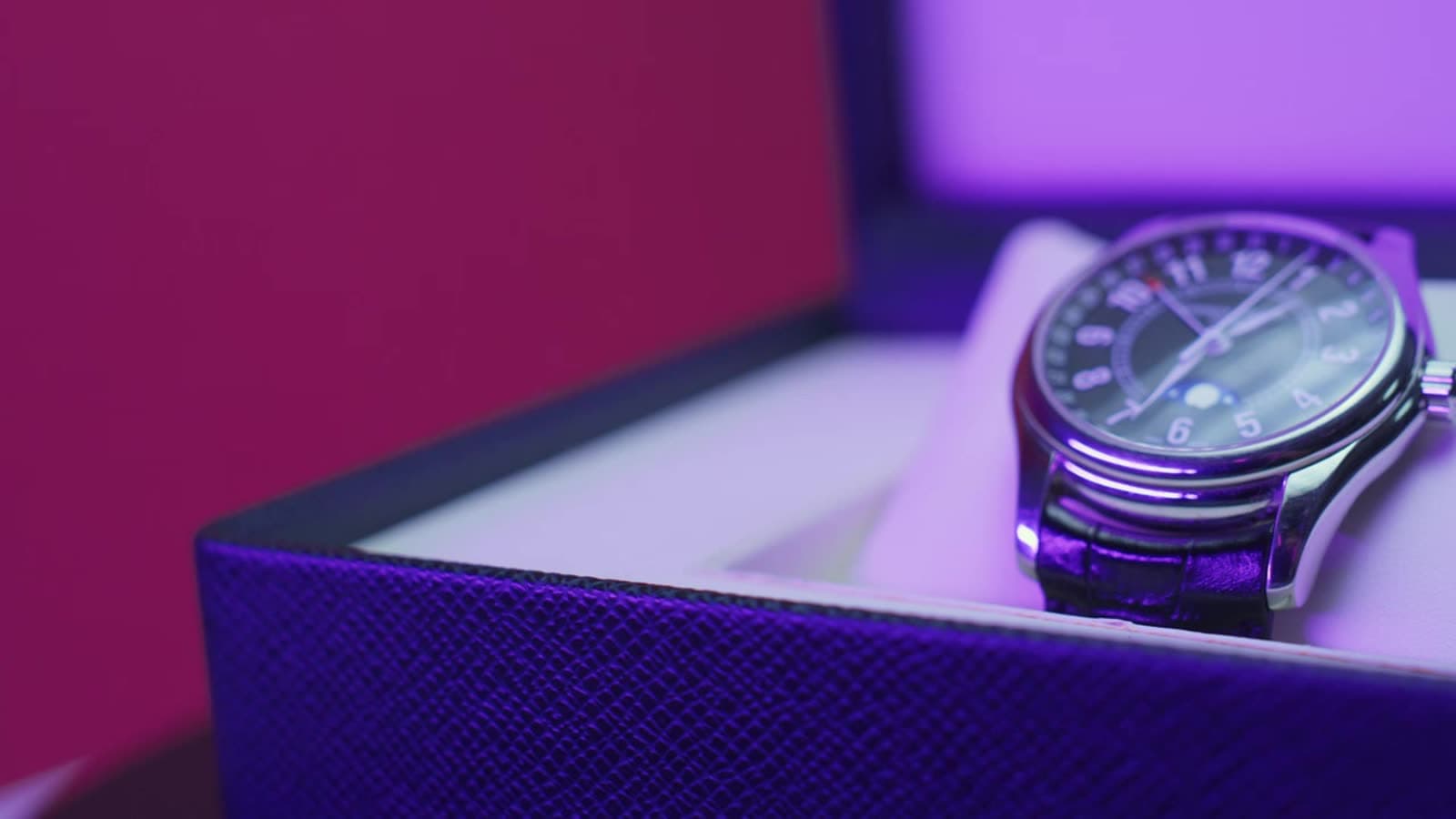 Close-up of a round dress watch with a dark dial and gold-tone hands